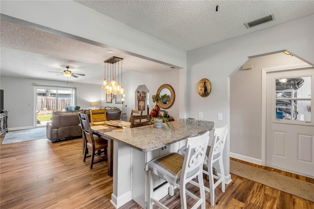 1205 Bond St, Edgewater, FL 32132 - kitchen featuring a textured ceiling, a kitchen breakfast bar, light wood finished floors, a peninsula, and light stone counters