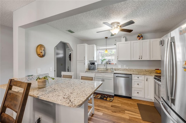 1205 Bond St, Edgewater, FL 32132 - kitchen featuring stainless steel appliances, a sink, a breakfast bar, a textured ceiling, and a peninsula