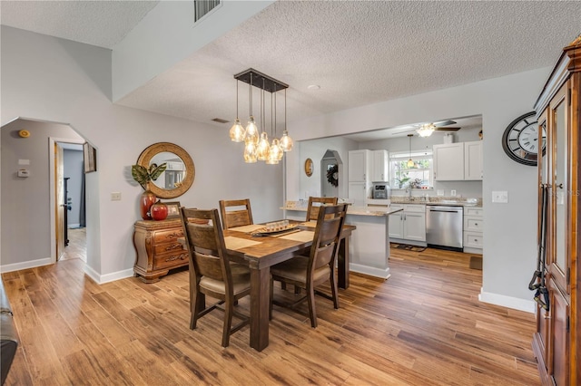 1205 Bond St, Edgewater, FL 32132 - dining room featuring light wood-type flooring, ceiling fan, a textured ceiling, arched walkways, and baseboards