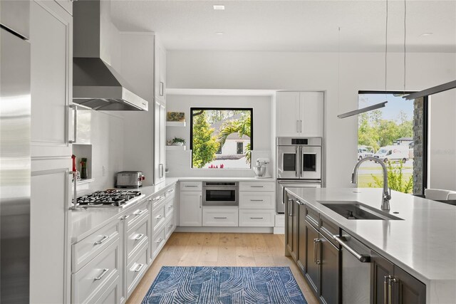 1624 Turnbull Crossings Dr, New Smyrna Beach, FL 32168 - kitchen featuring wall chimney exhaust hood, stainless steel appliances, a sink, light countertops, and light wood-style flooring