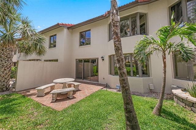 2961 Oceans Trce, Daytona Beach Shores, FL 32118 - back of house featuring stucco siding, a patio area, a lawn, and a tile roof