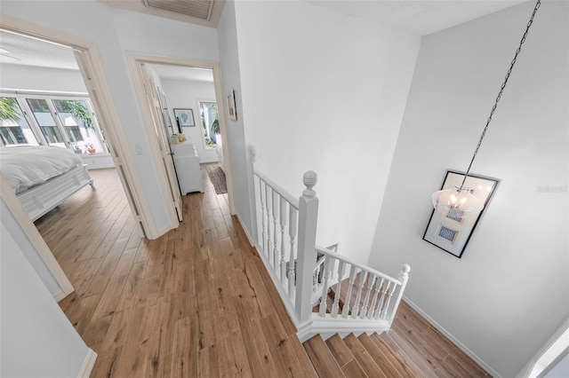 2961 Oceans Trce, Daytona Beach Shores, FL 32118 - hallway featuring an upstairs landing, light wood-style flooring, a chandelier, and baseboards