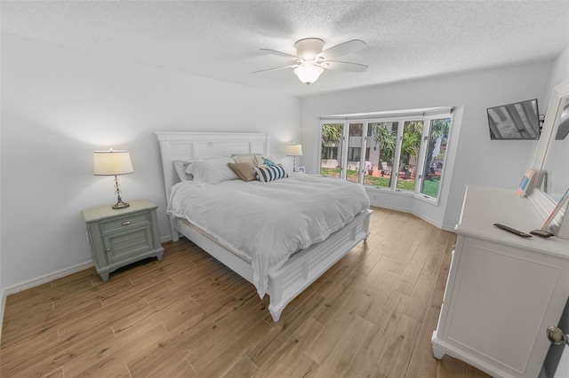 2961 Oceans Trce, Daytona Beach Shores, FL 32118 - bedroom with light wood-style flooring, a textured ceiling, a ceiling fan, and baseboards