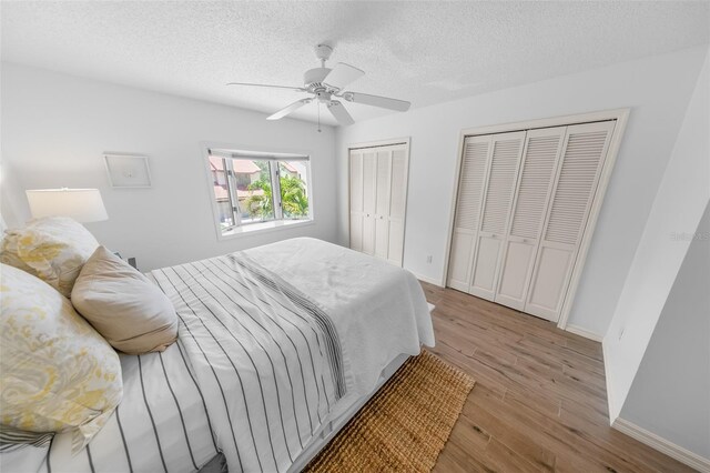 2961 Oceans Trce, Daytona Beach Shores, FL 32118 - bedroom with two closets, light wood-type flooring, baseboards, a textured ceiling, and a ceiling fan