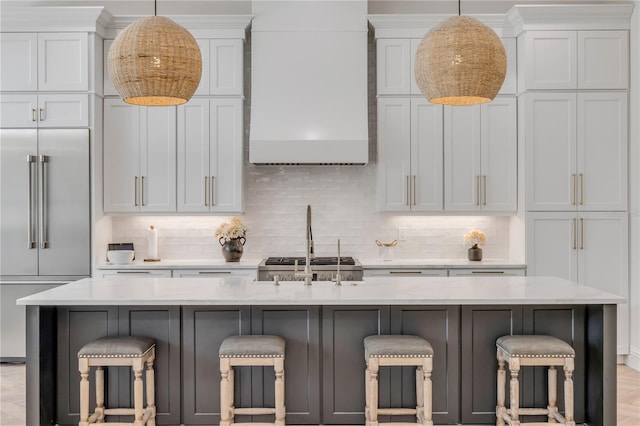 102 Inlet Shores Dr, New Smyrna Beach, FL 32168 - kitchen featuring built in fridge, tasteful backsplash, wall chimney range hood, and pendant lighting