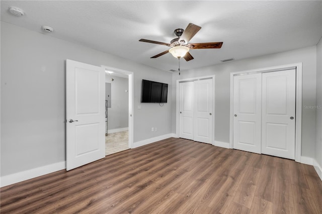 1144 Corbin Park Rd, New Smyrna Beach, FL 32168 - unfurnished bedroom with multiple closets, wood finished floors, baseboards, and ceiling fan