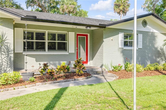 1144 Corbin Park Rd, New Smyrna Beach, FL 32168 - view of front of home with brick siding, a front yard, and roof with shingles