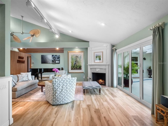 1215 Commodore Dr, New Smyrna Beach, FL 32168 - living area featuring vaulted ceiling, wood finished floors, a fireplace, a ceiling fan, and rail lighting