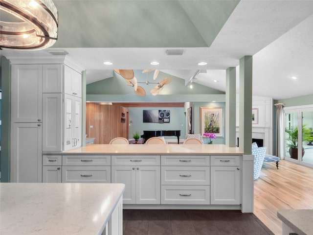 1215 Commodore Dr, New Smyrna Beach, FL 32168 - kitchen with lofted ceiling, white cabinets, a large fireplace, open floor plan, and recessed lighting