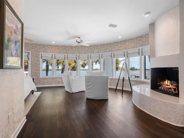 1215 Commodore Dr, New Smyrna Beach, FL 32168 - living area featuring wallpapered walls, dark wood-style floors, a premium fireplace, healthy amount of natural light, and ceiling fan