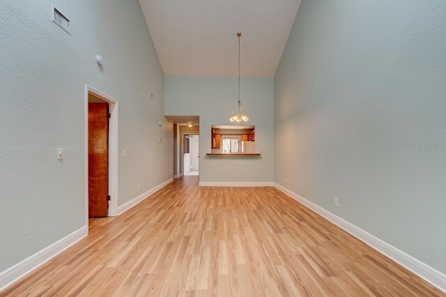488 Shorewood Ln, New Smyrna Beach, FL 32168 - unfurnished living room featuring high vaulted ceiling, light wood-style floors, baseboards, and a chandelier