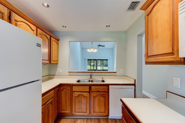 488 Shorewood Ln, New Smyrna Beach, FL 32168 - kitchen with white appliances, a sink, light countertops, light wood finished floors, and a chandelier