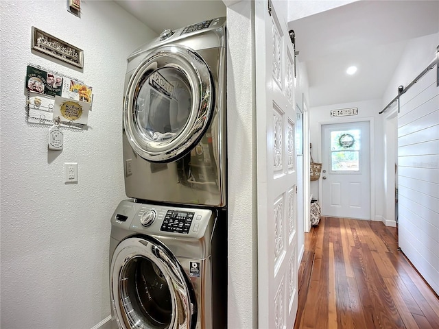 216 Murray St, New Smyrna Beach, FL 32168 - washroom with stacked washer / dryer, a barn door, hardwood / wood-style floors, a textured wall, and baseboards