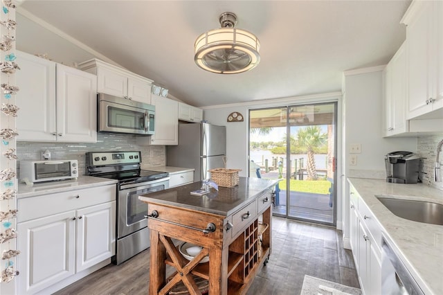 76 Heather Point Ct, New Smyrna Beach, FL 32169 - kitchen with stainless steel appliances, a sink, lofted ceiling, decorative backsplash, and light wood-style floors