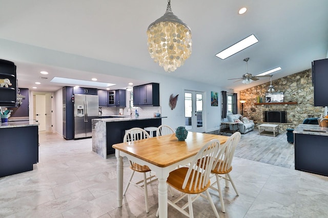 475 Spruceview Dr, Port Orange, FL 32127 - dining area with a stone fireplace, a ceiling fan, recessed lighting, a skylight, and lofted ceiling