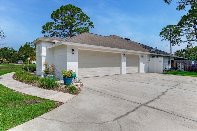 484 Sweet Bay Ave, New Smyrna Beach, FL 32168 - view of side of property with a garage, driveway, stucco siding, and roof with shingles