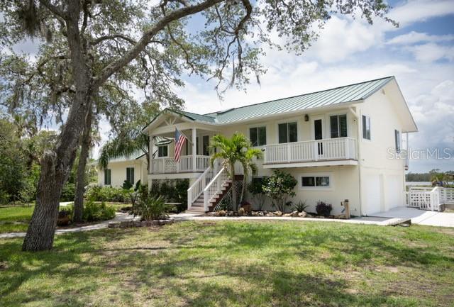 2950 Sunset Dr, New Smyrna Beach, FL 32168 - beach home with stairs, a standing seam roof, a garage, a front lawn, and concrete driveway