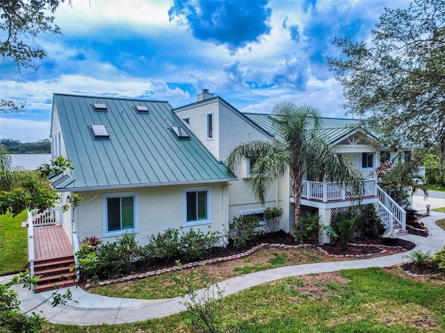 2950 Sunset Dr, New Smyrna Beach, FL 32168 - view of front of house featuring a standing seam roof, metal roof, a chimney, and a porch