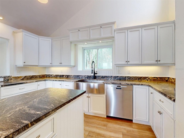 2950 Sunset Dr, New Smyrna Beach, FL 32168 - kitchen with dishwasher, a sink, light wood-style flooring, vaulted ceiling, and dark stone counters