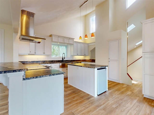 2950 Sunset Dr, New Smyrna Beach, FL 32168 - kitchen with island exhaust hood, high vaulted ceiling, a peninsula, light wood-style flooring, and a sink