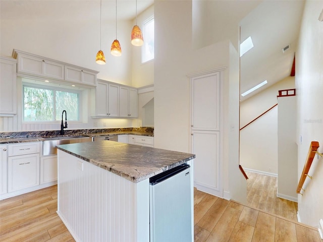 2950 Sunset Dr, New Smyrna Beach, FL 32168 - kitchen featuring a sink, high vaulted ceiling, light wood-style floors, dark stone counters, and healthy amount of natural light