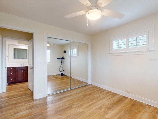 2950 Sunset Dr, New Smyrna Beach, FL 32168 - unfurnished bedroom with a sink, a closet, baseboards, light wood-type flooring, and a ceiling fan