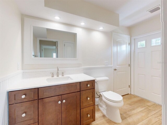 2950 Sunset Dr, New Smyrna Beach, FL 32168 - bathroom with wainscoting, vanity, toilet, a decorative wall, and recessed lighting