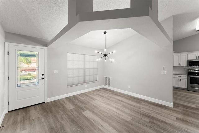 2325 Lime Tree Dr, Edgewater, FL 32141 - unfurnished living room featuring a textured ceiling, wood finished floors, a chandelier, baseboards, and lofted ceiling