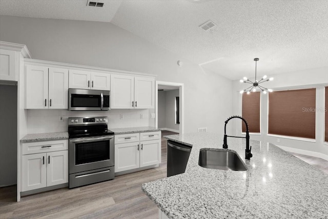 2325 Lime Tree Dr, Edgewater, FL 32141 - kitchen featuring stainless steel appliances, a sink, vaulted ceiling, white cabinets, and light wood-style flooring