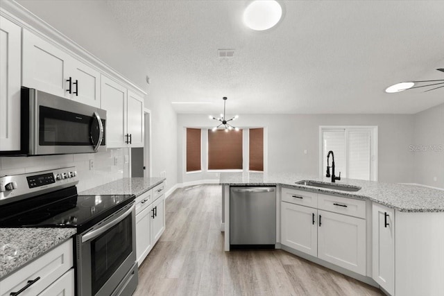 2325 Lime Tree Dr, Edgewater, FL 32141 - kitchen featuring stainless steel appliances, a sink, light wood-style flooring, a chandelier, and white cabinetry