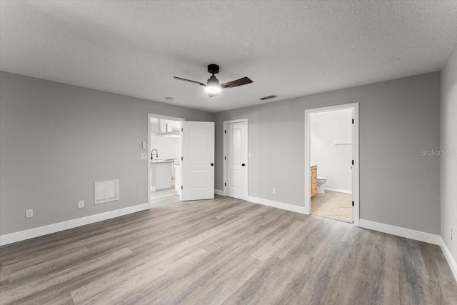 2325 Lime Tree Dr, Edgewater, FL 32141 - unfurnished bedroom with light wood-style floors, baseboards, a textured ceiling, ensuite bath, and ceiling fan