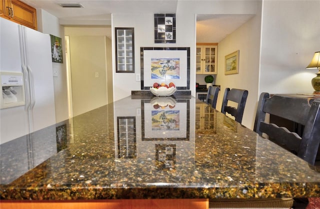 4435 S Atlantic Ave Unit 416, Port Orange, FL 32127 - kitchen featuring white fridge with ice dispenser, dark stone counters, and brown cabinetry