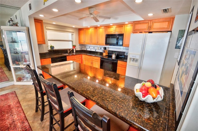 4435 S Atlantic Ave Unit 416, Port Orange, FL 32127 - kitchen with black appliances, a tray ceiling, a sink, a breakfast bar area, and recessed lighting