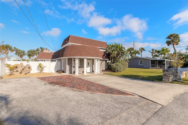 2900 S Peninsula Dr, Daytona Beach, FL 32118 - back of property with roof with shingles, a sunroom, driveway, and mansard roof