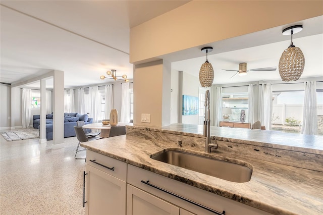 2900 S Peninsula Dr, Daytona Beach, FL 32118 - kitchen with open floor plan, a sink, dark aggregate flooring, light stone countertops, and decorative light fixtures