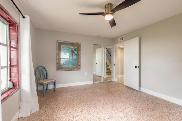 2900 S Peninsula Dr, Daytona Beach, FL 32118 - unfurnished bedroom featuring speckle patterned floor, baseboards, a closet, a ceiling fan, and multiple windows