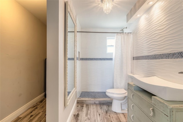 2900 S Peninsula Dr, Daytona Beach, FL 32118 - bathroom with toilet, wood finished floors, a tile shower, vanity, and baseboards