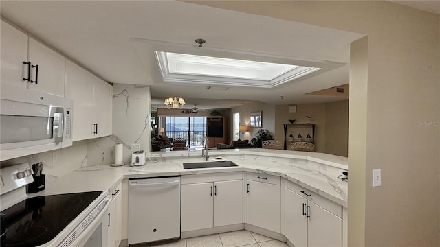 2700 N Peninsula Ave Unit 322, New Smyrna Beach, FL 32169 - kitchen with white appliances, a sink, white cabinets, light stone countertops, and a peninsula