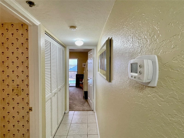 2700 N Peninsula Ave Unit 322, New Smyrna Beach, FL 32169 - corridor featuring a textured wall, a textured ceiling, light tile patterned flooring, and light carpet
