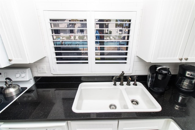 5301 S Atlantic Ave Unit 140, New Smyrna Beach, FL 32169 - kitchen view of a sink, white cabinets, tasteful backsplash, and dark stone counters