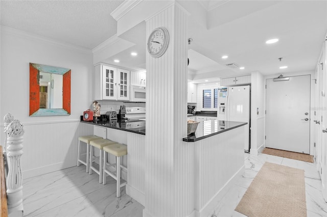 5301 S Atlantic Ave Unit 140, New Smyrna Beach, FL 32169 - kitchen with light marble finish floors, dark countertops, white appliances, a peninsula, and white cabinets