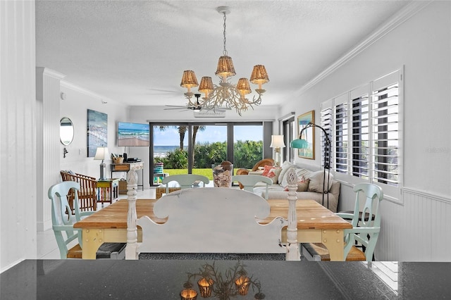 5301 S Atlantic Ave Unit 140, New Smyrna Beach, FL 32169 - dining room with crown molding, a chandelier, a textured ceiling, and a wainscoted wall
