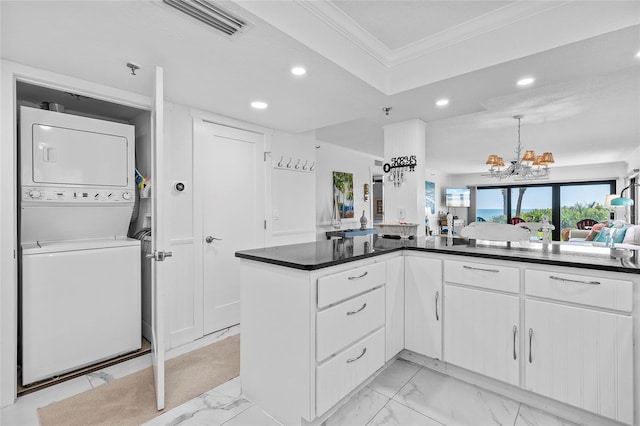 5301 S Atlantic Ave Unit 140, New Smyrna Beach, FL 32169 - kitchen featuring estacked washer and dryer, recessed lighting, ornamental molding, light marble finish flooring, and a chandelier