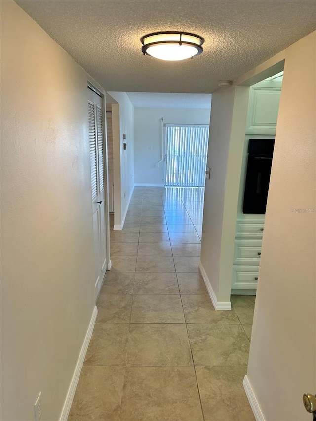 315 N Causeway Unit 2060, New Smyrna Beach, FL 32169 - corridor featuring a textured ceiling, baseboards, and light tile patterned floors