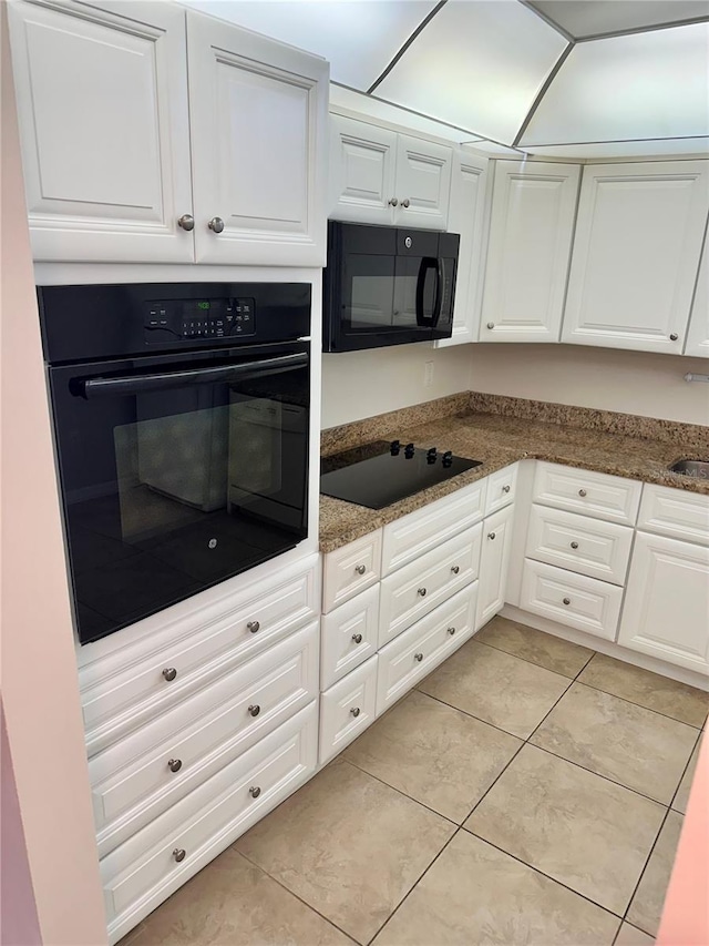 315 N Causeway Unit 2060, New Smyrna Beach, FL 32169 - kitchen with black appliances, light tile patterned floors, white cabinets, and dark stone countertops