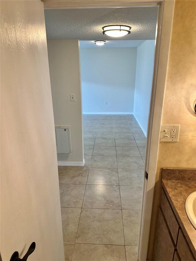 315 N Causeway Unit 2060, New Smyrna Beach, FL 32169 - hall featuring a textured ceiling, light tile patterned flooring, baseboards, and a sink