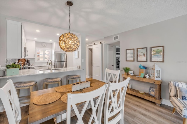 4151 S Atlantic Ave Unit 3090, New Smyrna Beach, FL 32169 - dining room featuring a barn door, light wood-style flooring, recessed lighting, and a chandelier