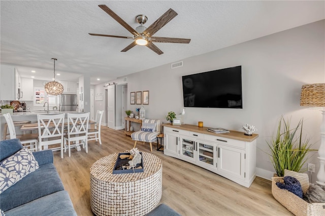 4151 S Atlantic Ave Unit 3090, New Smyrna Beach, FL 32169 - living room with ceiling fan, light wood-style flooring, a textured ceiling, and baseboards