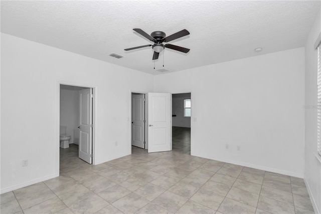 7223 SW 61st Pl, Ocala, FL 34474 - unfurnished bedroom with a textured ceiling, light tile patterned floors, ceiling fan, and connected bathroom