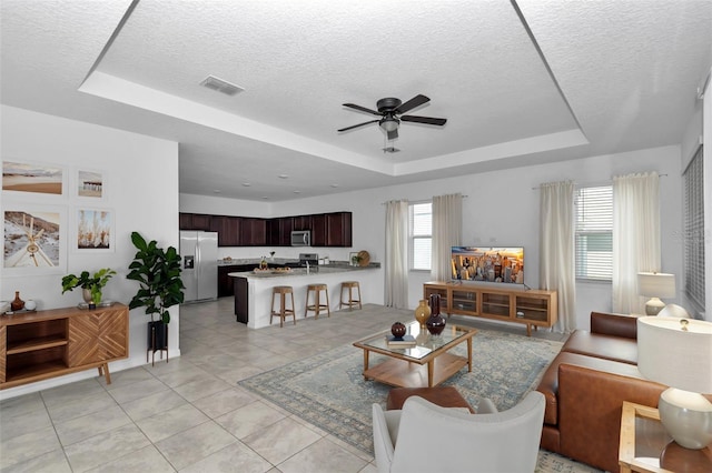 7223 SW 61st Pl, Ocala, FL 34474 - living room with a tray ceiling, a ceiling fan, a textured ceiling, and light tile patterned floors